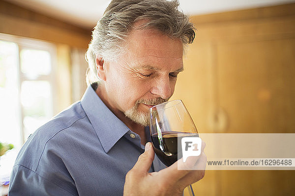 Close up serene man smelling and tasting red wine