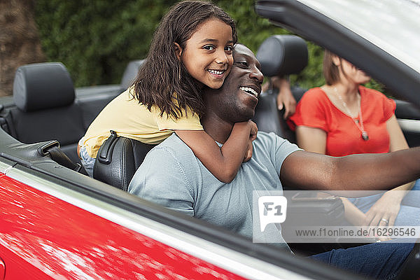 Portrait happy daughter hugging father driving convertible