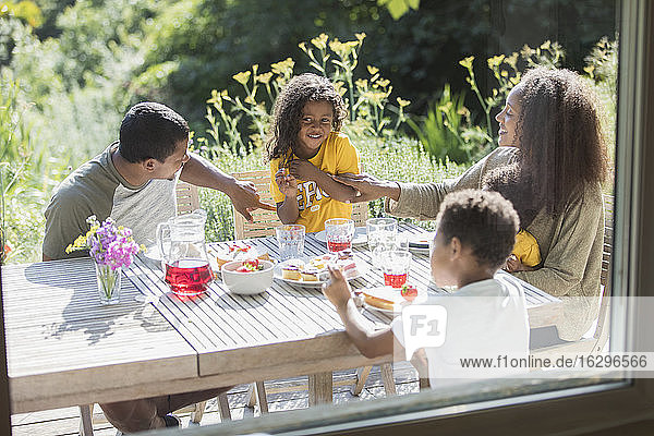 Glückliche Familie genießt das Mittagessen auf der sonnigen Sommerterrasse