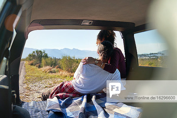 Zärtliches junges Paar genießt sonnige Aussicht auf die Natur vom Heck des Autos