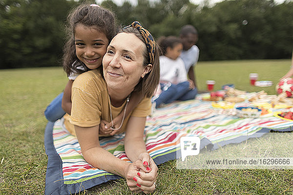 Porträt einer glücklichen Mutter und Tochter  die sich auf einer Picknickdecke im Park entspannen