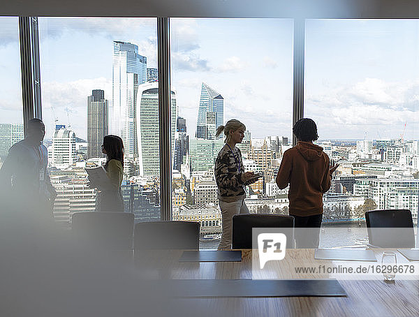 Geschäftsleute im Gespräch am Fenster eines Hochhausbüros  London  UK