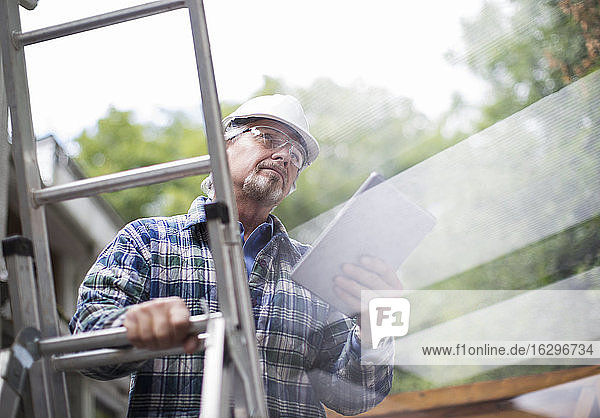Leitender Bauführer mit digitalem Tablett auf Leiter