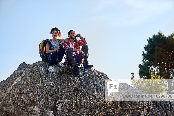 Happy young hiker couple relaxing on rock