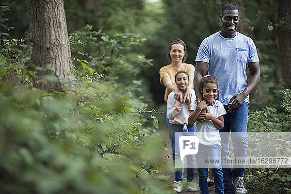 Happy family hiking on trail in woods