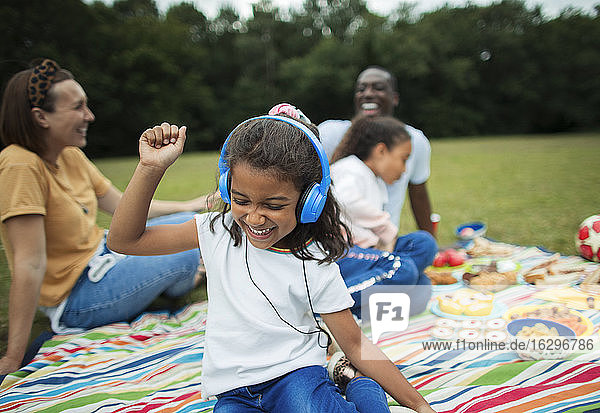 Sorgloses Mädchen  das mit Kopfhörern auf einer Picknickdecke Musik hört