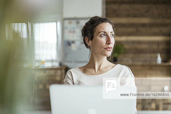 Close-up of female entrepreneur looking away while using laptop