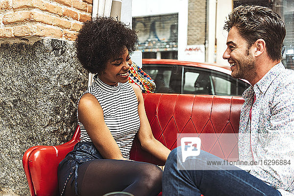 Fröhliches Paar im Gespräch auf dem Sofa vor dem Fenster in einem Restaurant