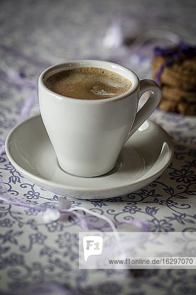 Tasse Kaffee und Schokoladenkekse auf gemustertem Tuch