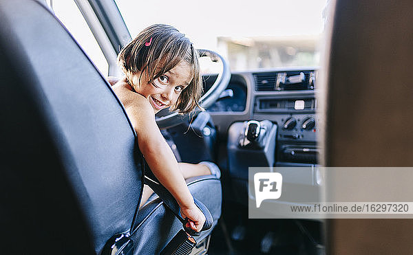 Nettes lächelndes Mädchen auf dem Fahrersitz