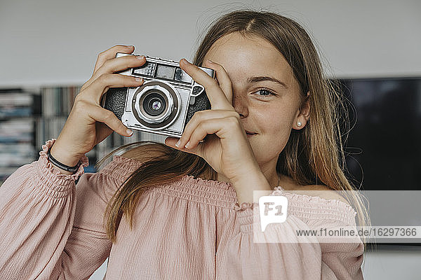 Nahaufnahme eines Mädchens  das mit einer alten Kamera zu Hause fotografiert