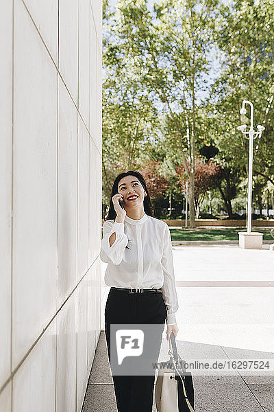 Lächelnde Unternehmerin  die in der Stadt ein Smartphone in die Hand nimmt
