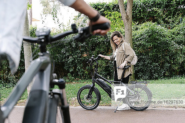 Smiling woman with electric bicycle on road