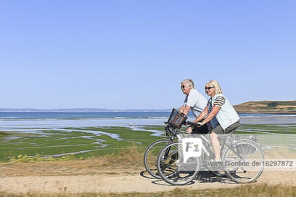 Frankreich  Bretagne  Finistere  Seniorenpaar auf E-Bikes an der Küste