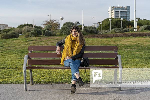 Junge Frau sitzt auf einer Bank im Park