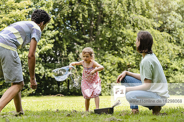 Familie spielt mit Seifenblase im Park