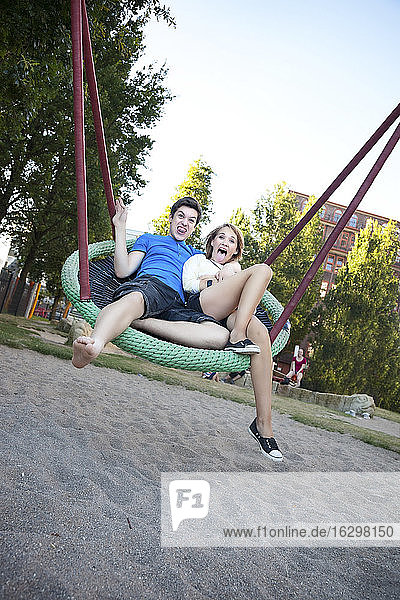 Teenage couple swinging at playground