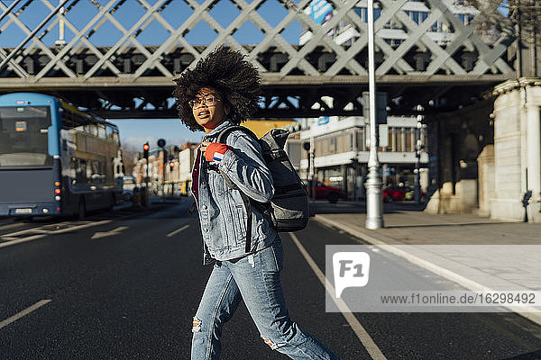 Junge Frau mit Afro-Haar  die an einem sonnigen Tag auf der Straße geht