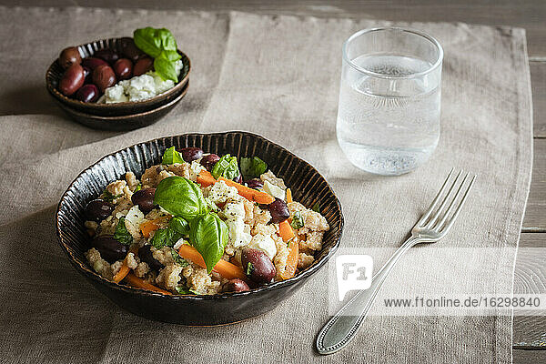 Schüssel mit vegetarischen Spätzle mit Karotten  Oliven  Fetakäse und Basilikum
