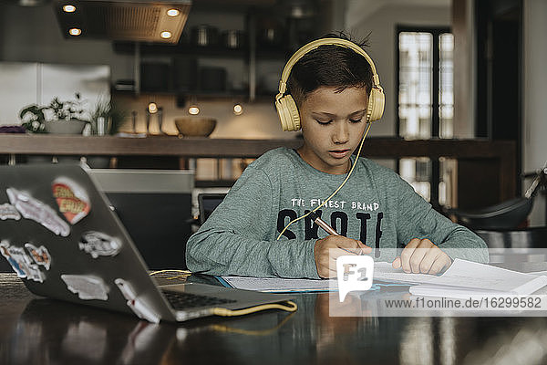 Schulkind lernt zu Hause mit Laptop und Kopfhörern