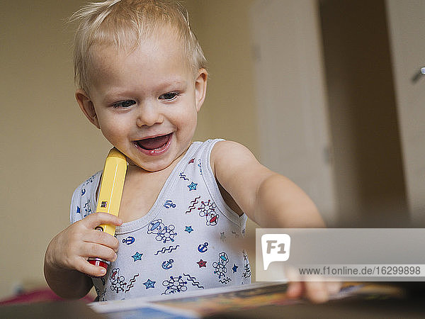 Cute happy baby playing with pencil at home