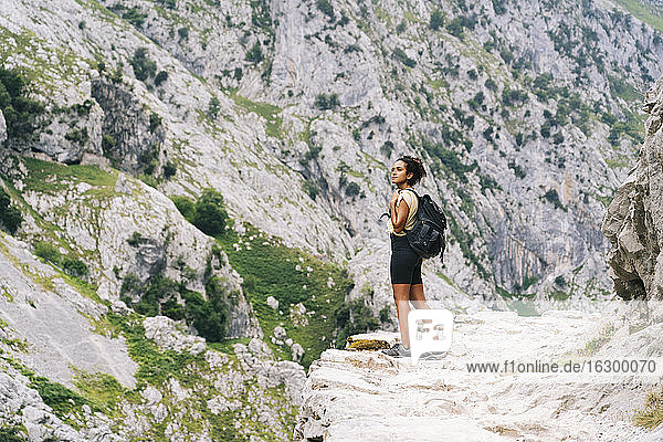 Frau mit Rucksack bewundert die Aussicht  während sie auf einem Bergpfad an der Ruta Del Cares steht  Asturien  Spanien