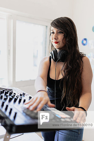 Lächelnde schöne weibliche Club-DJ mit Audio-Ausrüstung im Studio