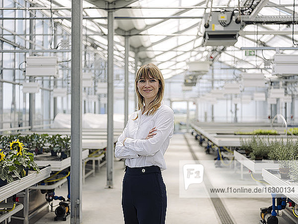 Smiling businesswoman with arms crossed standing in greenhouse