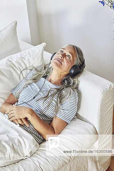 Nachdenkliche Frau beim Musikhören im Wohnzimmer