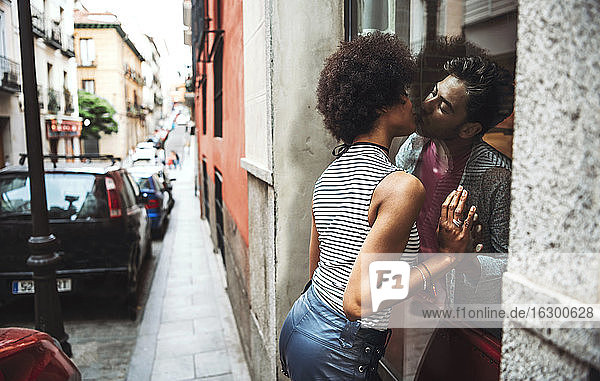 Romantisches Paar  das sich durch das Fenster eines Restaurants küsst