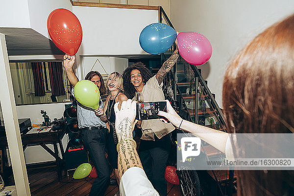 Frau fotografiert tanzende Freunde während einer Party zu Hause