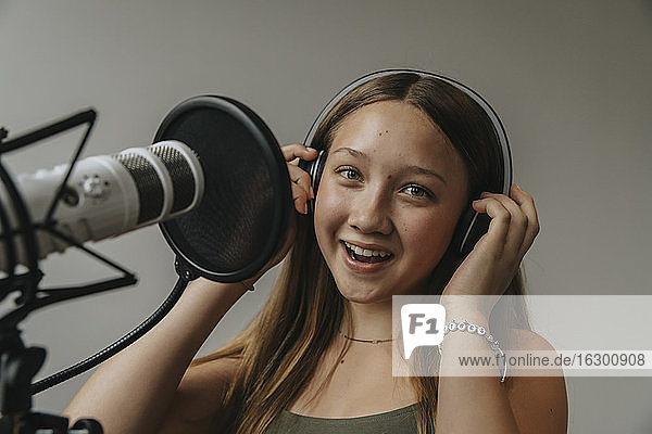 Nahaufnahme eines glücklichen Teenagers  der in einem Aufnahmestudio an der Wand singt