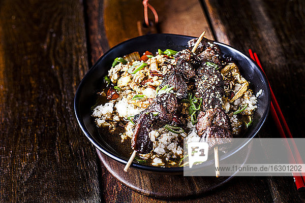 Schüssel mit verzehrfertigem Teriyaki-Reis mit Chinakohl und gegrillten Rindfleischspießchen