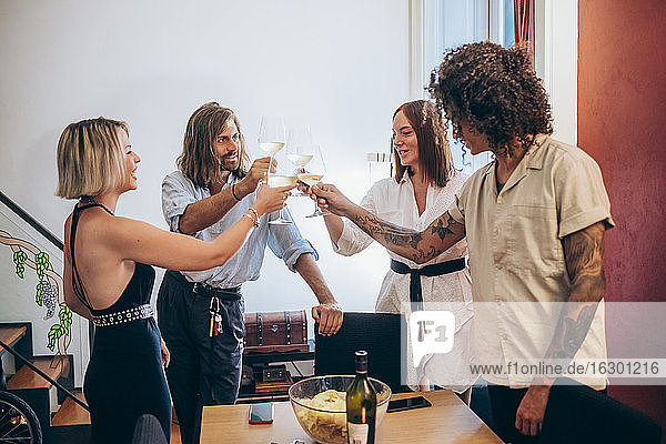 Männliche und weibliche Freunde stoßen mit Weingläsern während einer Party zu Hause an