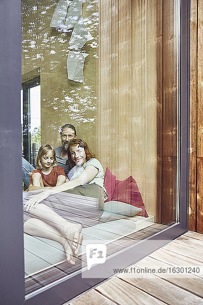 Familie  die sich zu Hause auf dem Bett entspannt  gesehen durch ein Fenster