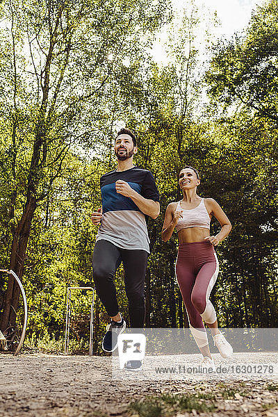 Sportlicher Mann und Frau laufen in der Nähe eines Fitnessparcours