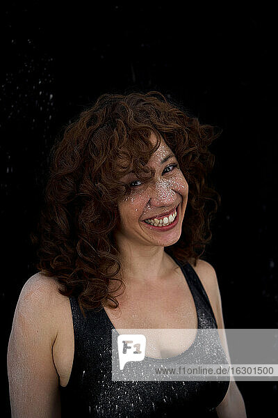 Fröhliche Frau mit von weißem Staub beflecktem Gesicht vor schwarzem Hintergrund