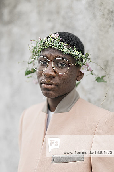 Junger Mann mit Brille und Blumen-Tiara auf der Stirn