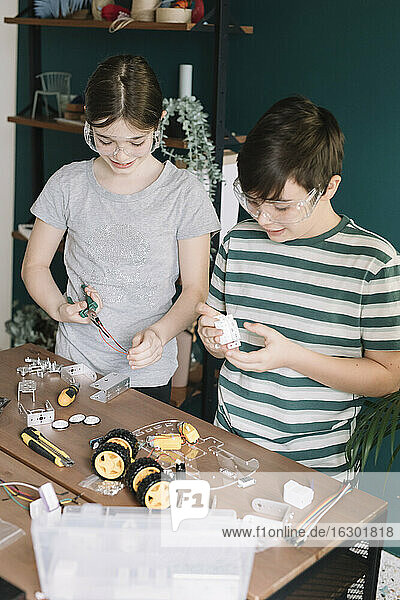 Geschwister bauen Roboterspielzeug auf dem Tisch zu Hause