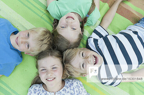Deutschland  Bayern  vier lachende Kinder auf einer Decke liegend