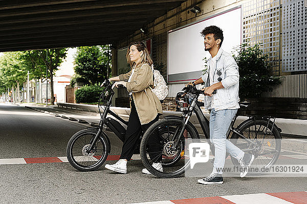 Couple crossing road with electric bicycles in city