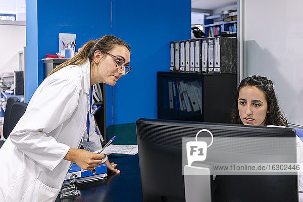 Kollegen diskutieren über den Computer auf dem Schreibtisch im Krankenhaus