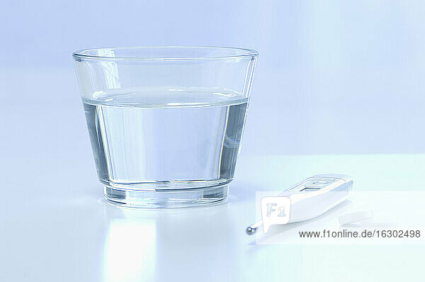 Fieberthermometer mit Wasserglas und Tabletten  Nahaufnahme