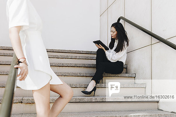 Geschäftsfrau steht neben einem Kollegen auf einer Treppe