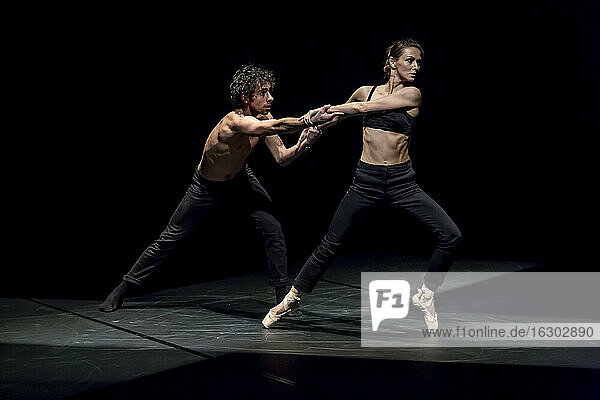 Tänzer und Tänzerin beim zeitgenössischen Ballett auf schwarzer Bühne