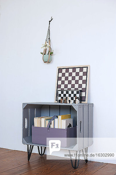 Schachbretter liegen auf einem selbstgebauten Bücherregal aus einer Holzkiste