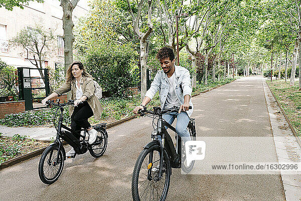 Couple riding electric bicycles on road
