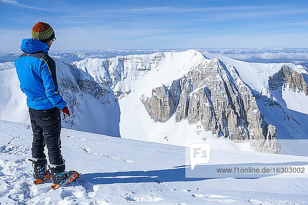 Junger Mann  der auf einem schneebedeckten Berg stehend die Aussicht betrachtet  Umbrien  Italien