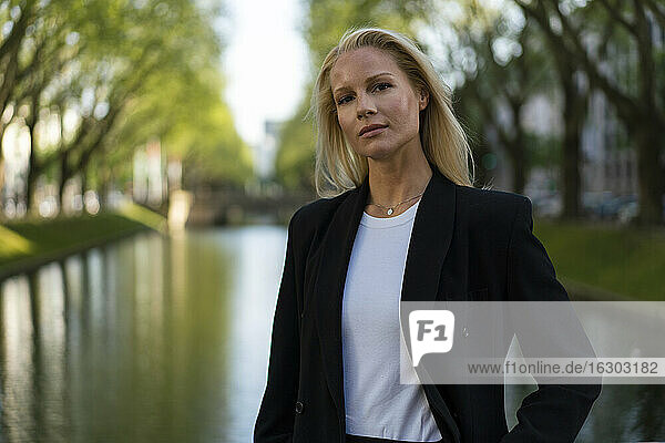 Schöne blonde Geschäftsfrau stehend gegen Kanal in der Stadt