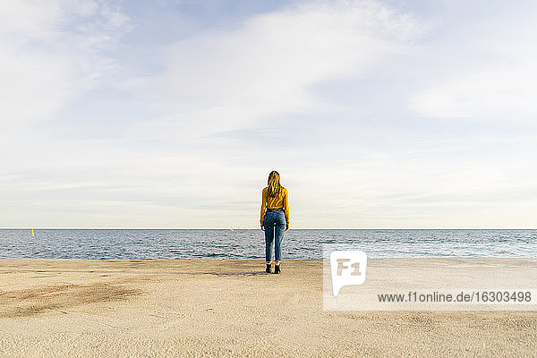 Young woman standing by sea against sky